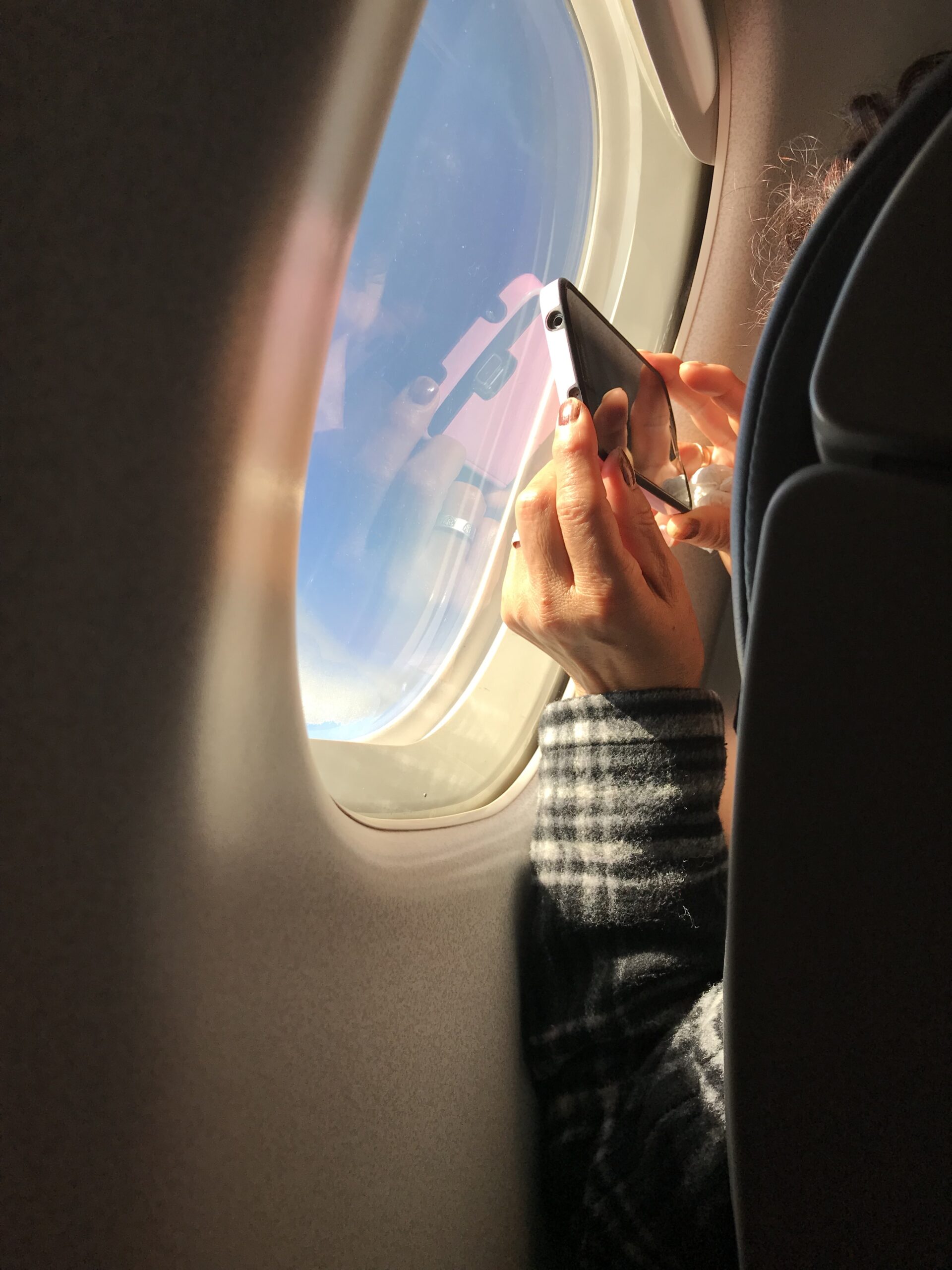 Hands taking photo out an airplane window